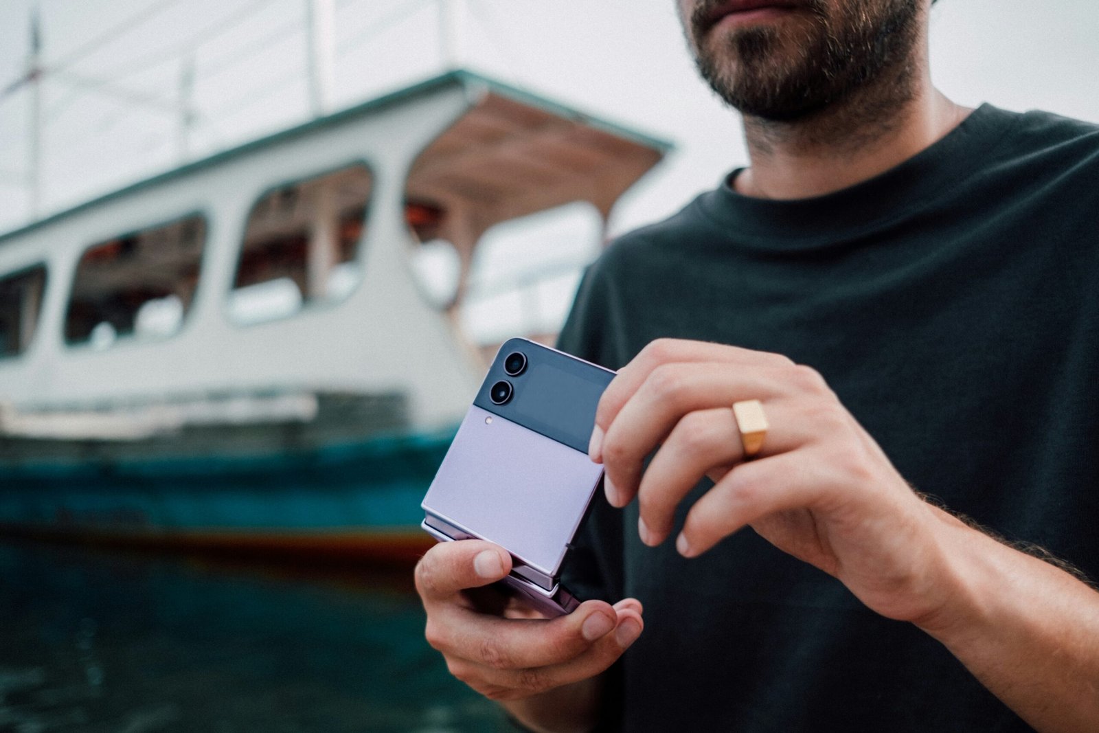 a man holding a cell phone in front of a boat